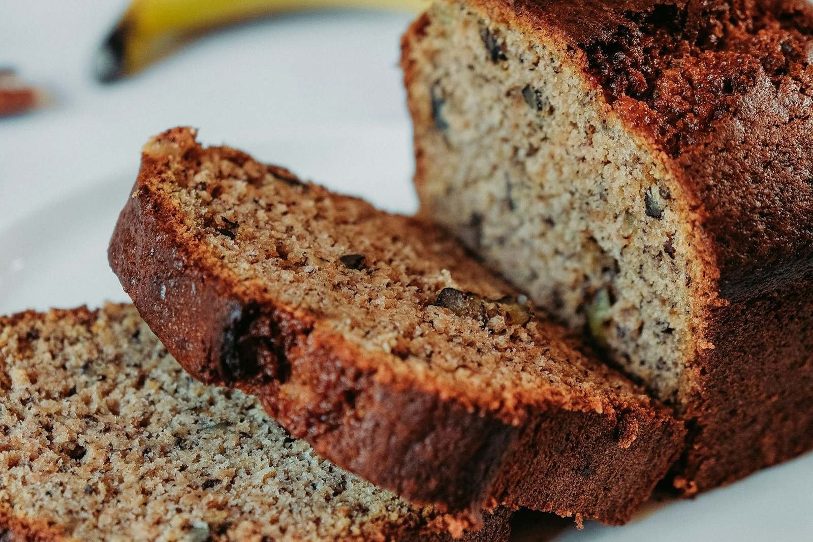 Thick slices of moist banana bread with dark chocolate flecks on a white plate