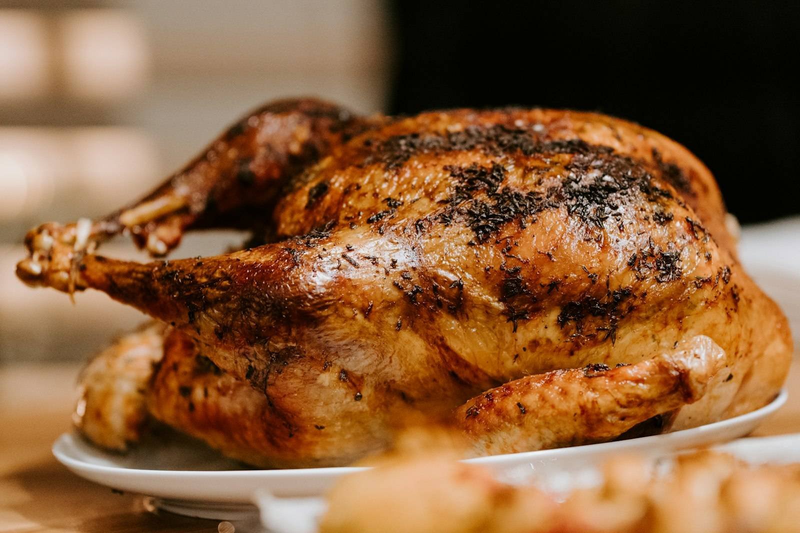 A golden roasted whole chicken with crisp herb-flecked skin on a serving plate