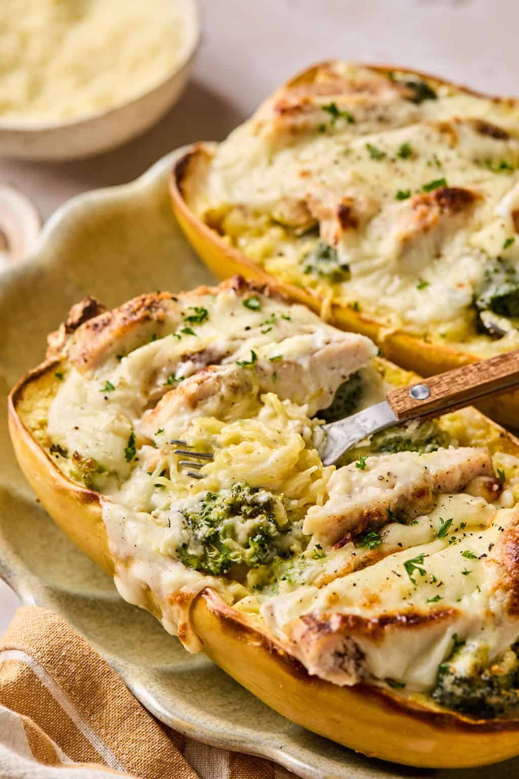 a fork scooping chicken alfredo spaghetti squash from the inside of the spaghetti squash.