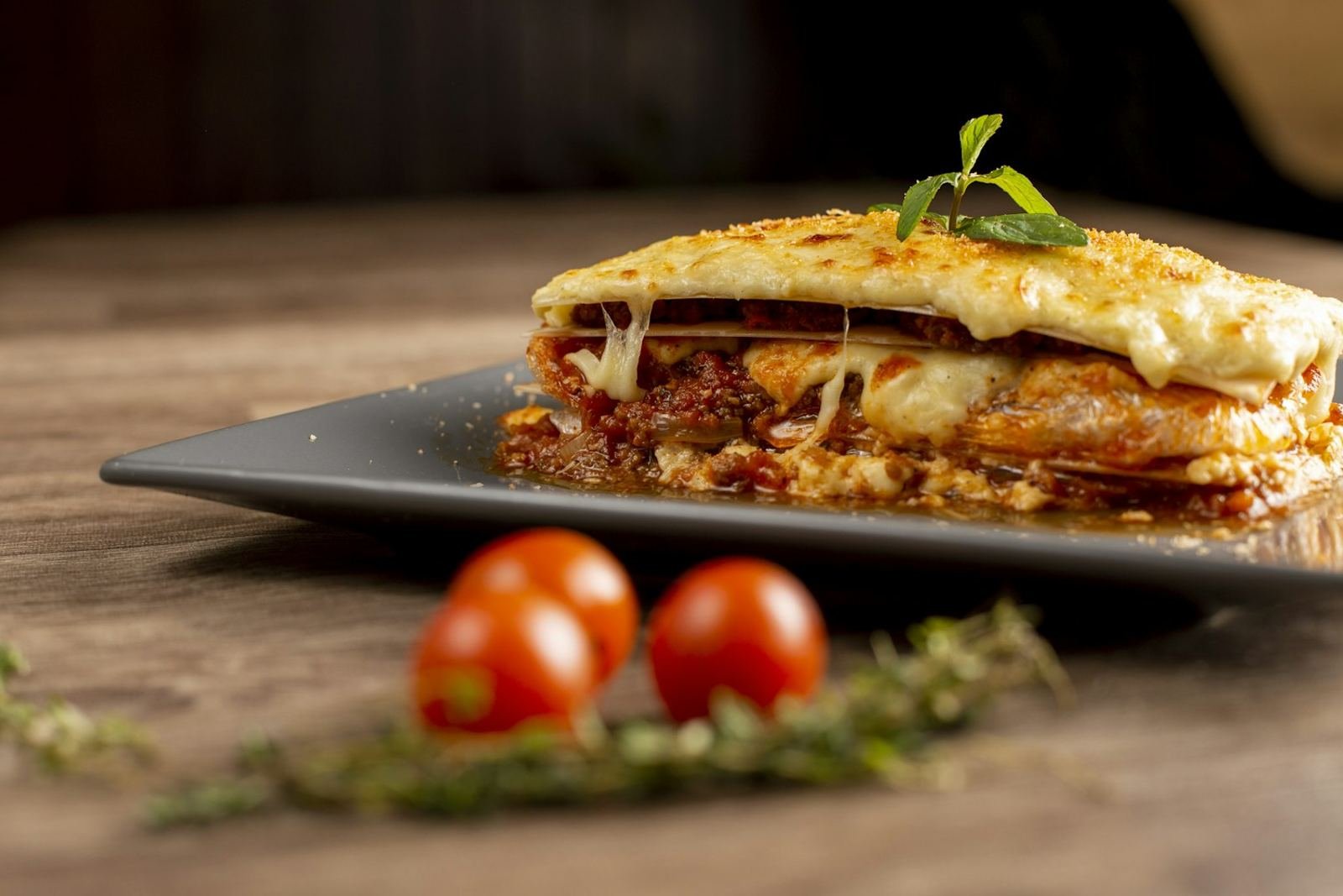 A golden-topped slice of beef lasagna with melted cheese on a plate